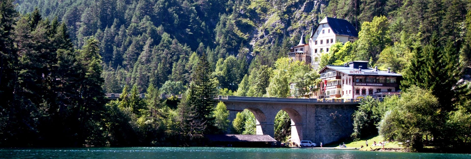 Schloss Hotel Fernsteinsee surrounded by woods, with the emerald green Fernsteinsee in the foreground (c) Schloss Hotel Fernsteinsee