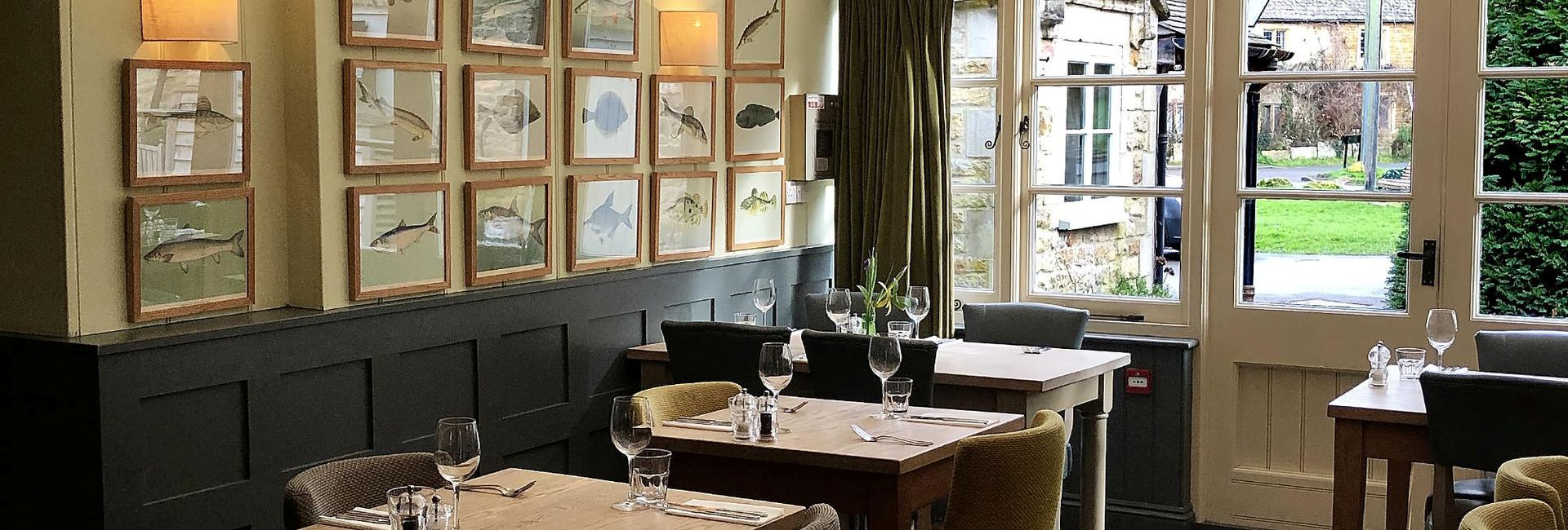 Interior of the restaurant at the King's Head Inn with woodden tables, chairs and framed pictures of fish on the wall