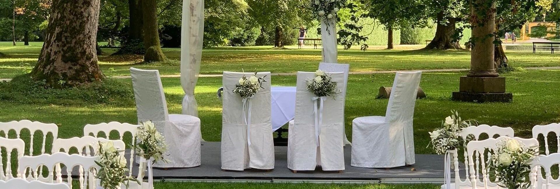 Solemnly prepared grandstand and white chairs for a civil wedding ceremony in the park of Schloss Hellbrunn in Salzburg